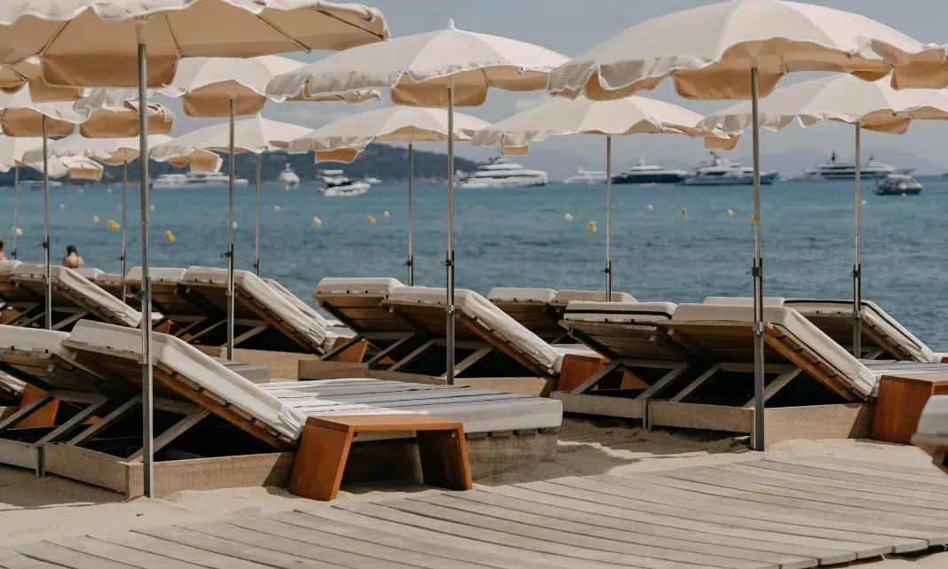 Transats et parasols de la plage priv&eacute;e Indie Beach Ramatuelle avec yachts et &icirc;les en fond