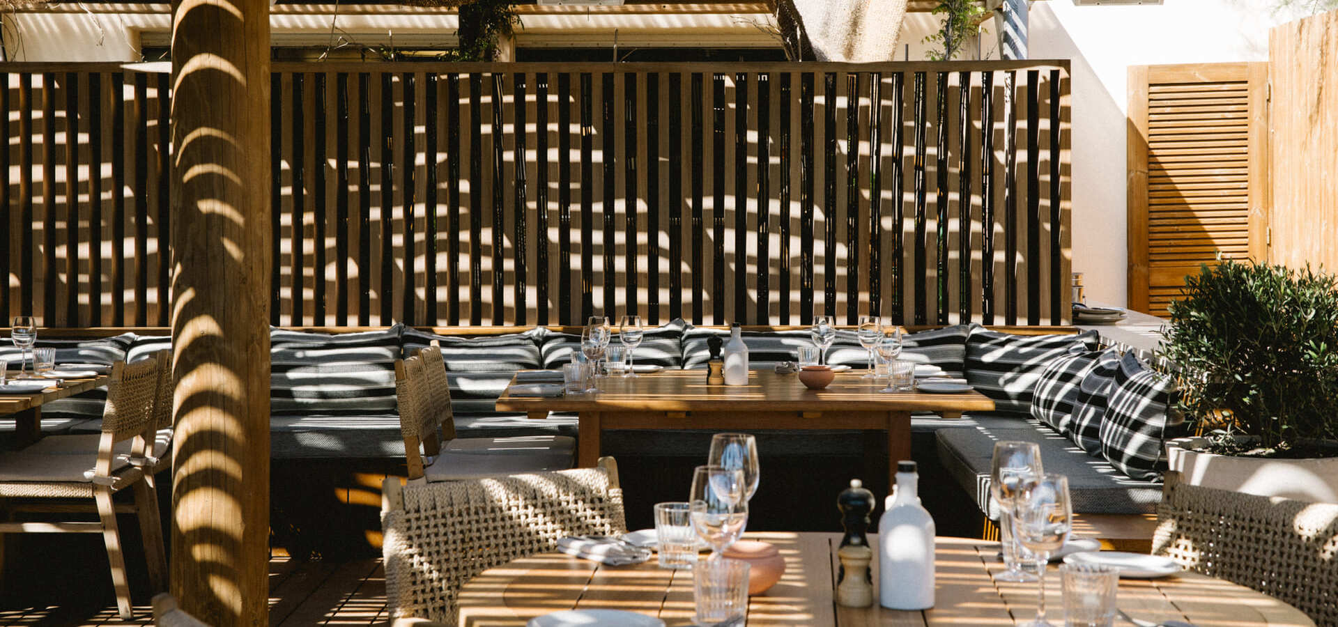 Espace détente du restaurant Pampelonne, terrasse en bois, oliviers et planches de surf